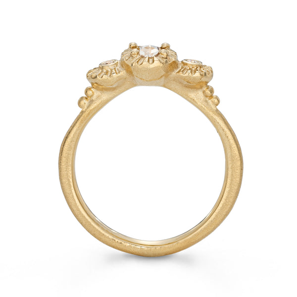 Gold ring with a central diamond and three smaller diamonds on a white background